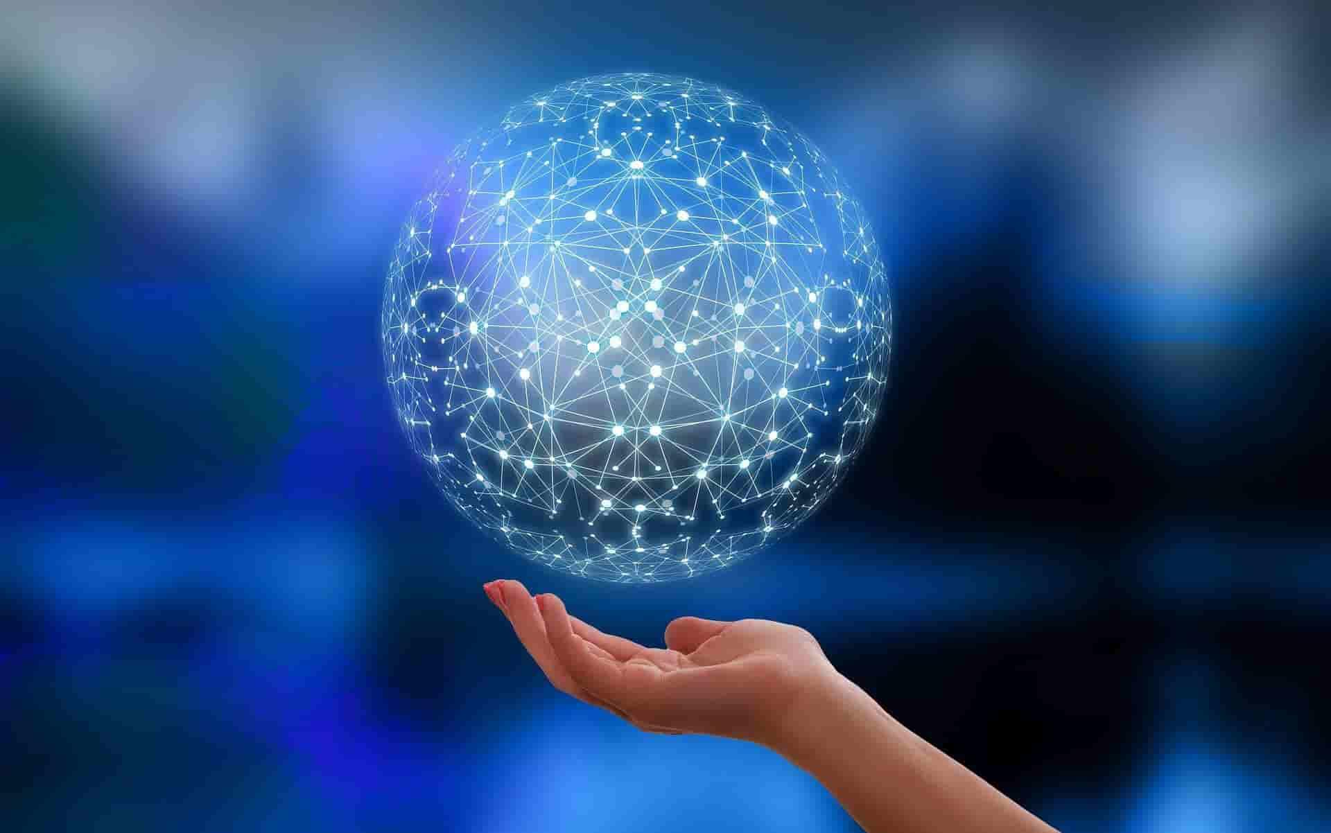 Imagem em animação com a palma de uma mão virada para cima, bem próxima de uma esfera vazada com inúmeros pontos brilhantes interligados, sugerindo conexões. O fundo é em azul degradê
