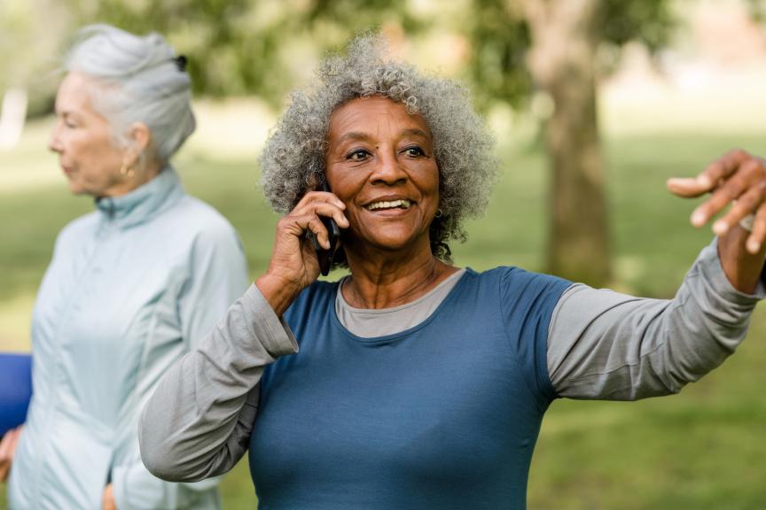 A woman on her phone smiling in the park