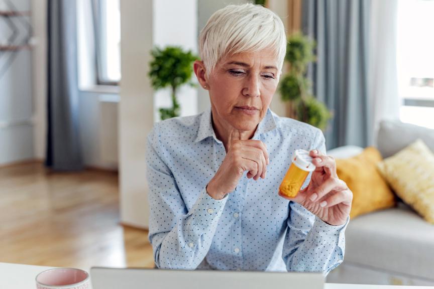 Elderly woman holding a medicine container in her hand