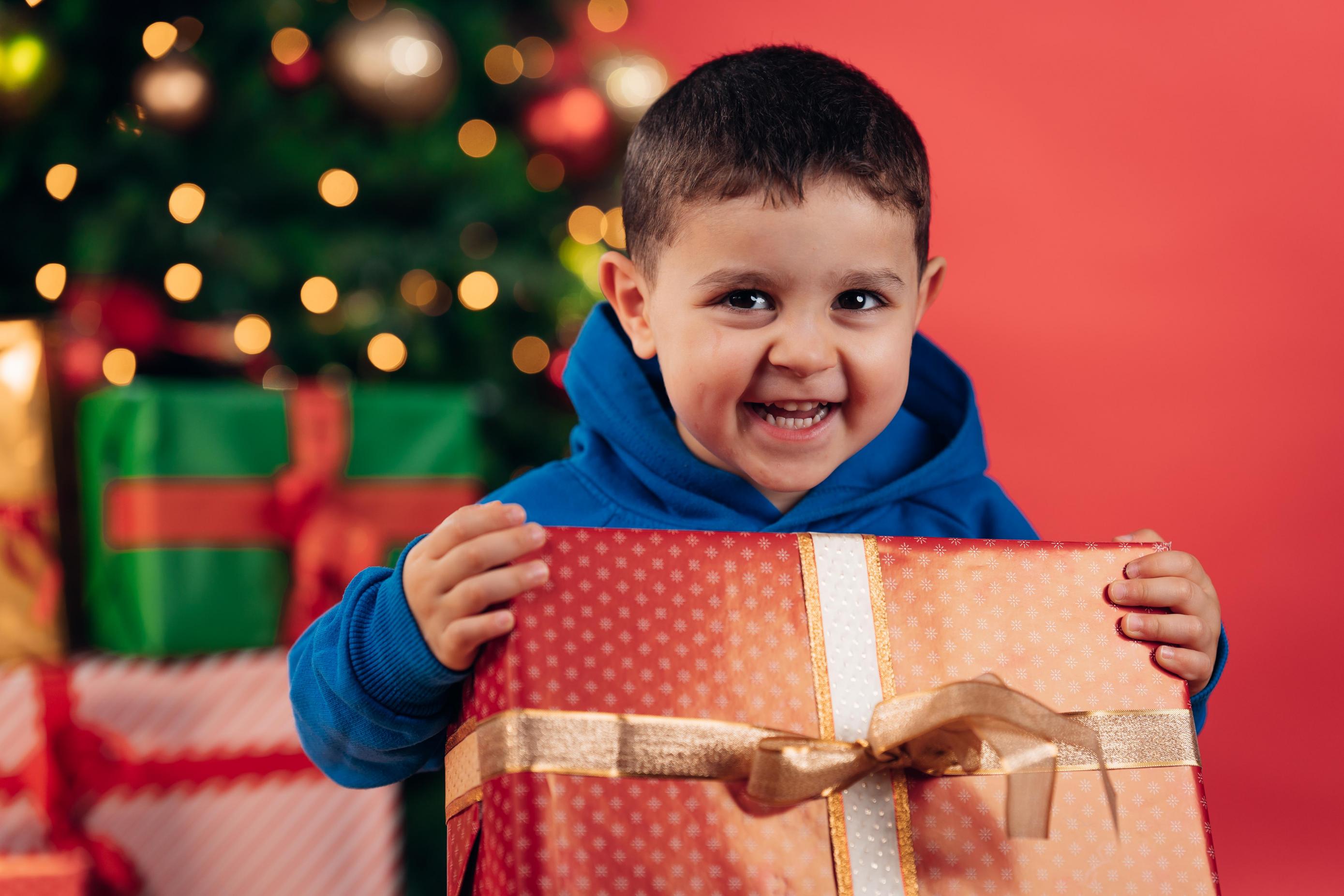 Young boy with christmas present in front of a christmas tree
